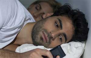 ベッドで携帯電話を持つカップル